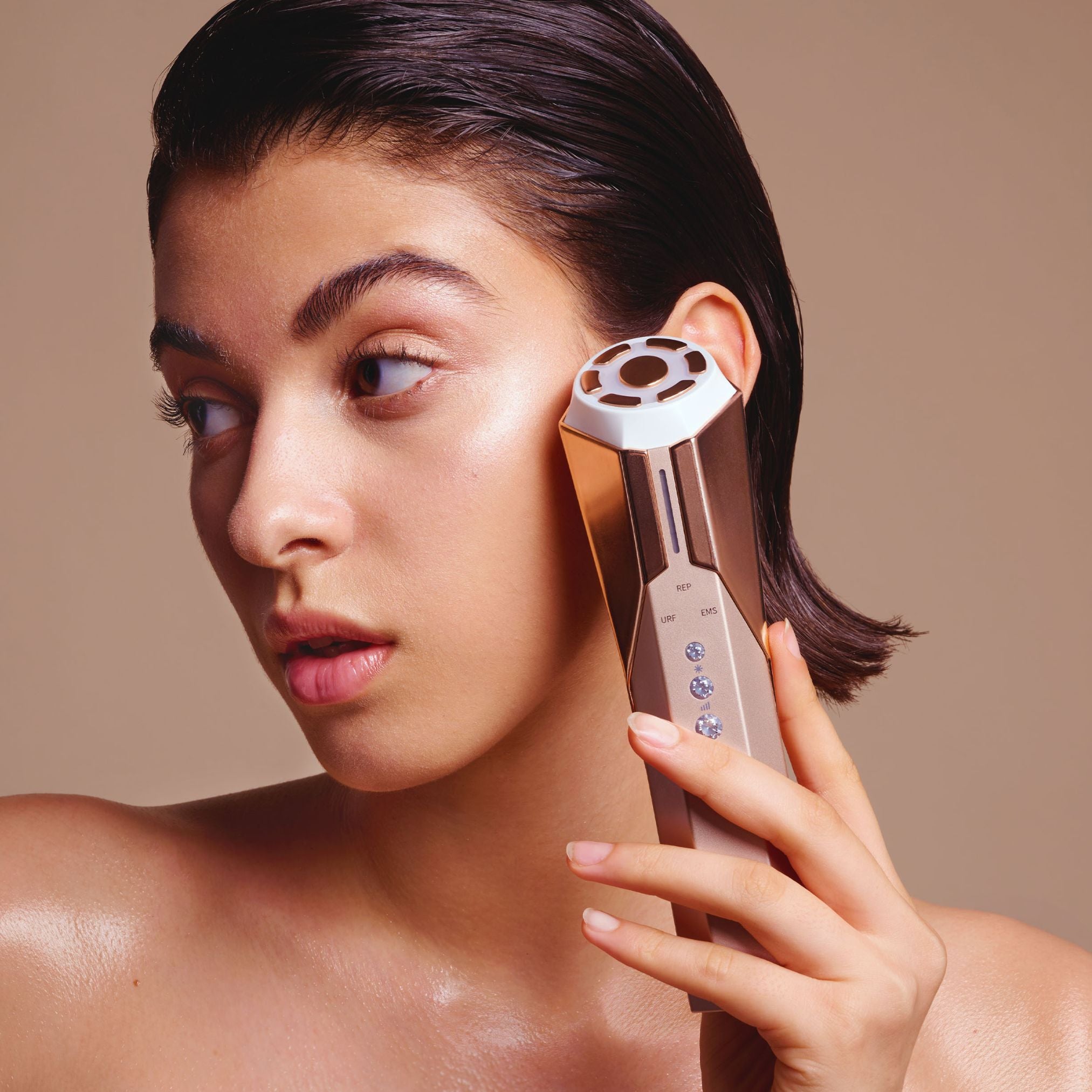 Woman gently gliding the Reva Instant Age Renewal Wand across her jawline and cheek.