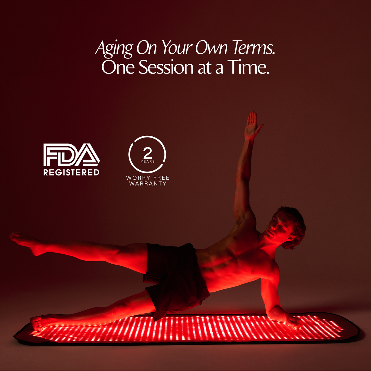 Man holding a side plank on the illuminated Restora red light therapy mat beside FDA-registered and 2-year warranty badges
