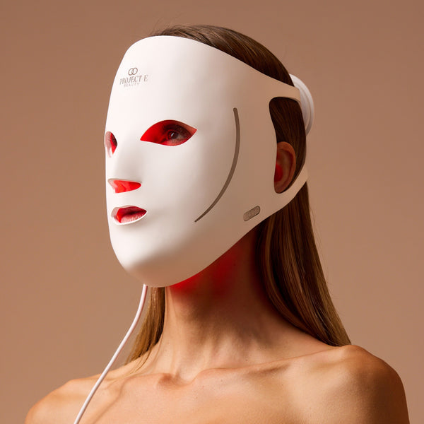 Woman wearing the white LumaLux Face V2 mask with red light glowing through the eye, nose and mouth openings