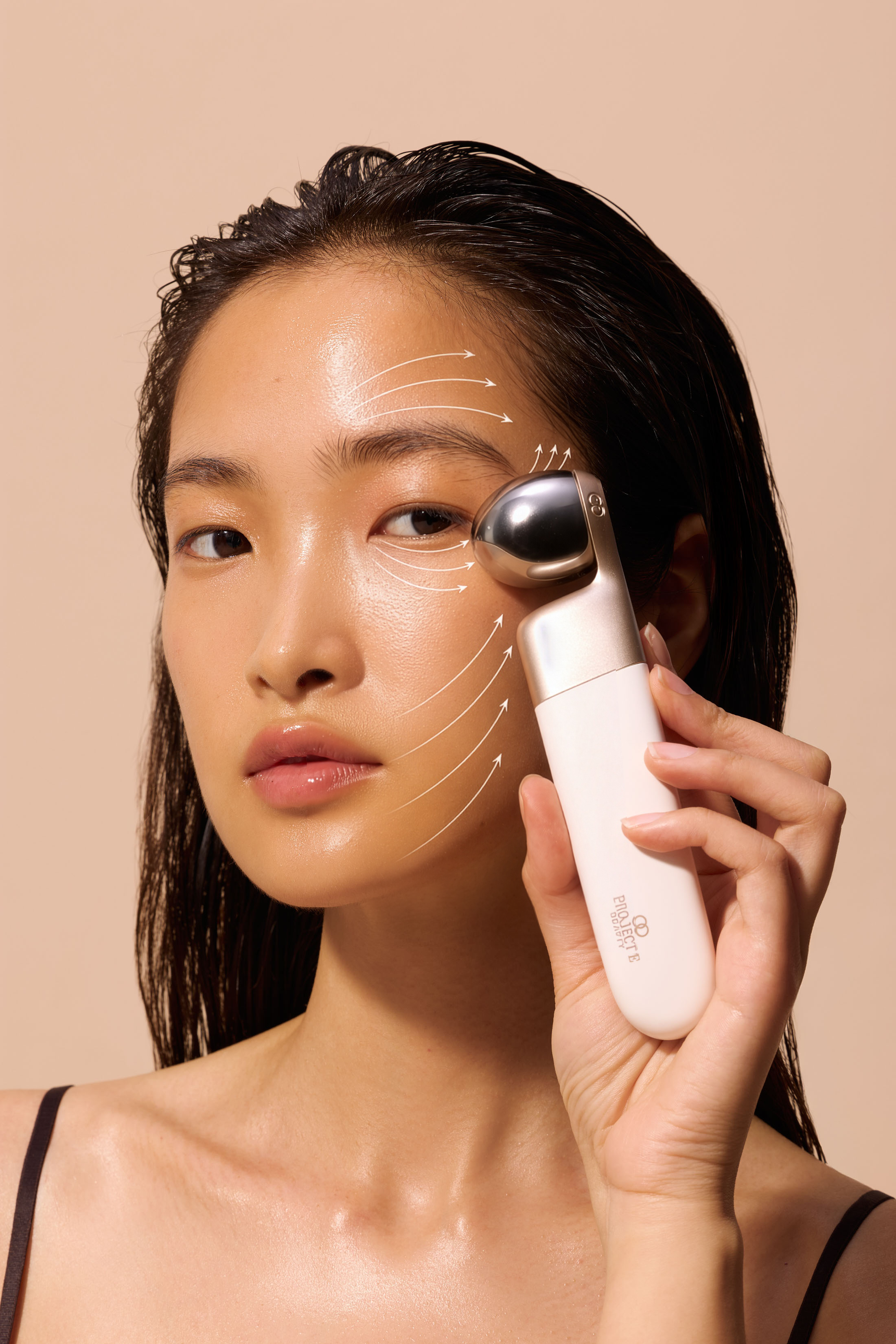 Model demonstrating facial massage roller with upward lift arrows.